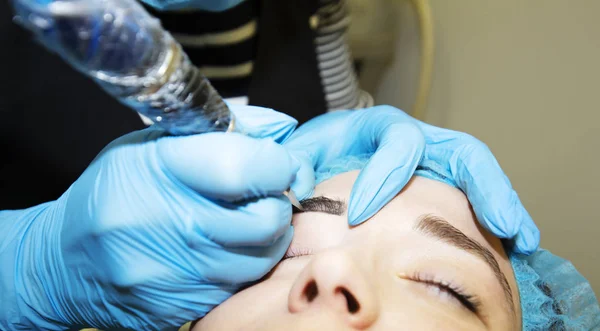 Cosmetologist aplicando a composição permanente nas sobrancelhas — Fotografia de Stock