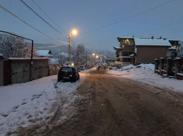 Kvällen utsikt över stan, snö på vägen. Träd i snön. Mountain ski resort Bakuriani — Stockfoto