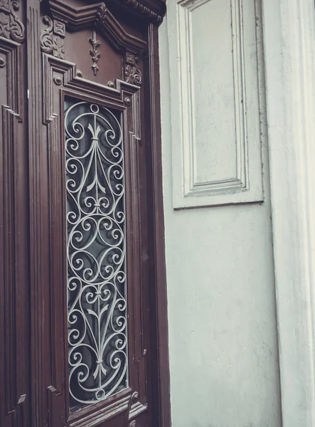 Porta de madeira de vidro de um edifício na rua com um ornamento decorativo de ferro. Arquitetura antiga de Tbilisi — Fotografia de Stock
