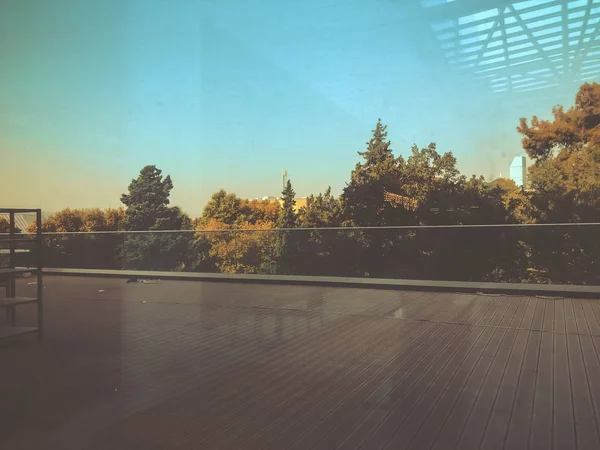 Belle vue sur les arbres contre le ciel bleu depuis le centre commercial moderne "Galleria" à Tbilissi, Géorgie. Réflexion dans la fenêtre en verre — Photo