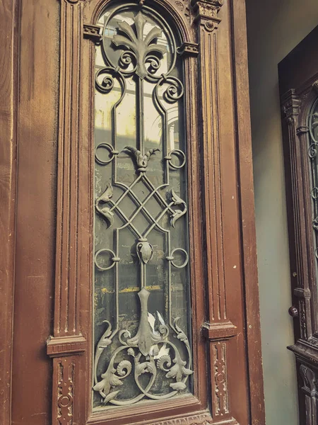 Glass wooden door of a building on the street with an iron decorative ornament. Old Tbilisi architecture — Stock Photo, Image