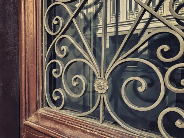 Reflexão de um edifício na rua em uma porta de madeira de vidro com um ornamento decorativo de ferro. Arquitetura antiga de Tbilisi — Fotografia de Stock