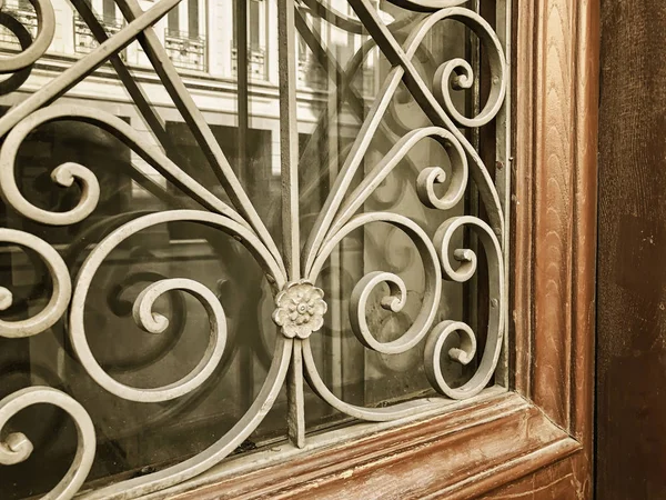 Reflejo de un edificio en la calle en una puerta de madera de cristal con un adorno decorativo de hierro. Arquitectura antigua de Tiflis — Foto de Stock