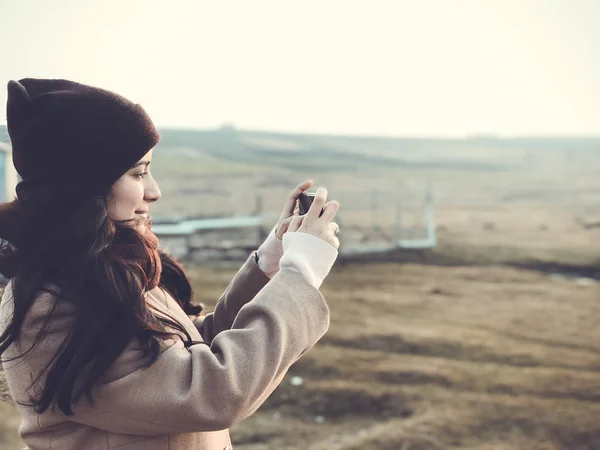 Lvov, Ukrajina - 2. března 2019: Dívka v klobouku a kabát fotí na smartphone — Stock fotografie