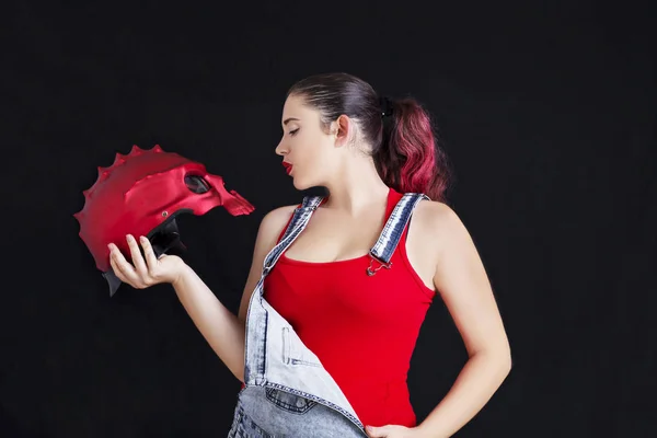 Una mujer joven en overoles de mezclilla y casco de ciclismo rojo en negro b — Foto de Stock