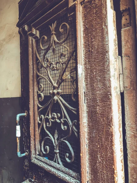 Wooden door of a building on the street with an iron decorative ornament. Old Tbilisi architecture — Stock Photo, Image