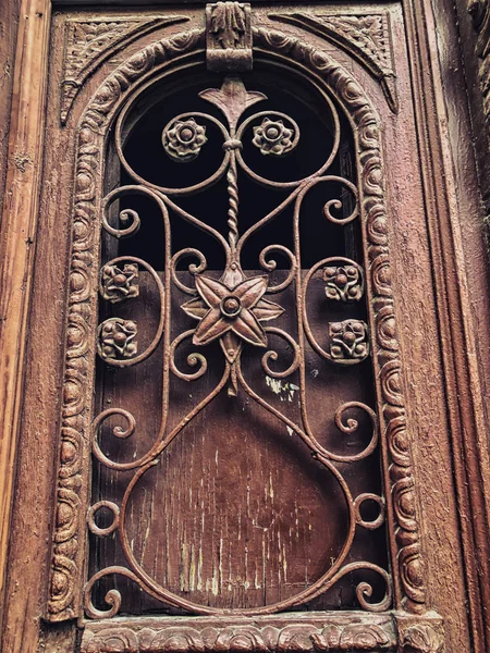 Detail of wooden door of a building on the street with an iron decorative ornament. Old Tbilisi architecture — Stock Photo, Image