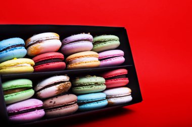 Tasty farklı macarons kara kutu kırmızı bir arka plan üzerinde renkli
