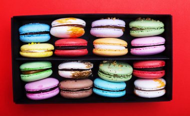 Tasty farklı macarons kara kutu kırmızı bir arka plan üzerinde renkli