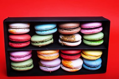 Tasty farklı macarons kara kutu kırmızı bir arka plan üzerinde renkli