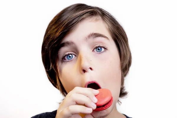 Feliz chico guapo comiendo el macaron sobre fondo blanco . — Foto de Stock