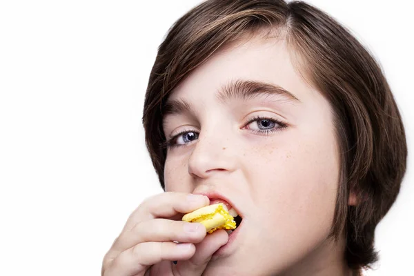 Feliz chico guapo comiendo el macaron sobre fondo blanco . — Foto de Stock