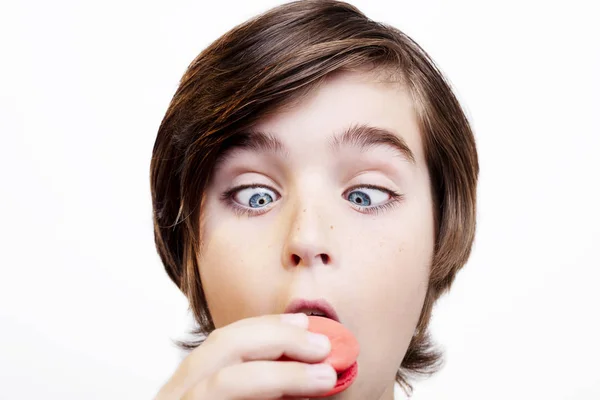 Glücklich schöner Junge isst die Macaron auf weißem Hintergrund. — Stockfoto