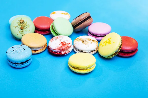 Tasty different colored macarons on blue background