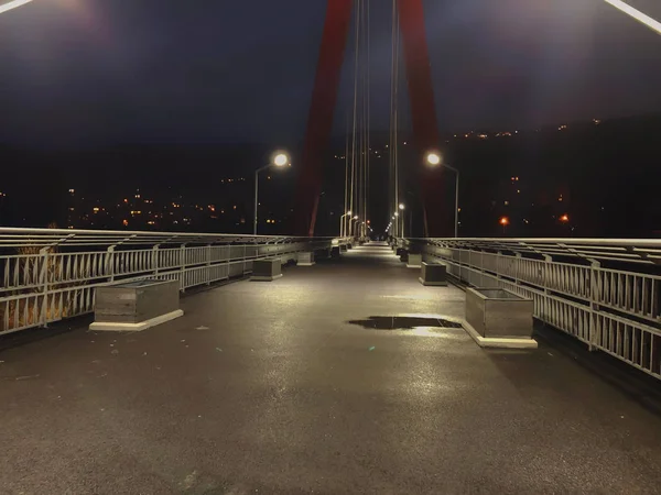 Zone de trottoir passant par un pont à haubans avec de gros câbles en acier, gros plan la nuit dans des lumières vives — Photo
