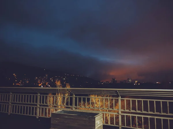 Área de calçada passando por uma ponte de cabo. Abertura da vista noturna para a cidade noturna — Fotografia de Stock