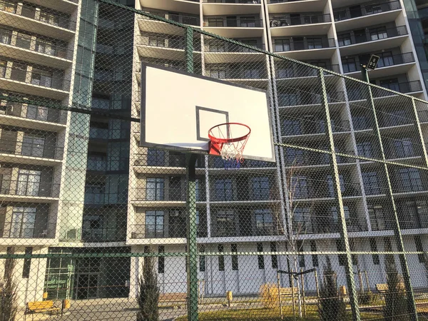 Basketball basket and board on the sports ground in the city yard near the new building