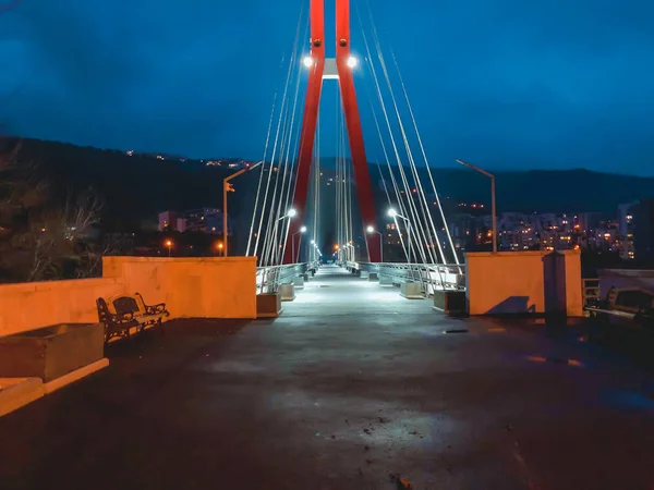 Zone de trottoir passant par un pont à haubans avec de gros câbles en acier, gros plan la nuit dans des lumières vives — Photo