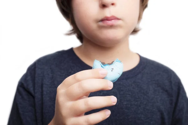 Knappe jongen houdt in zijn handen macaroni over witte achtergrond. — Stockfoto