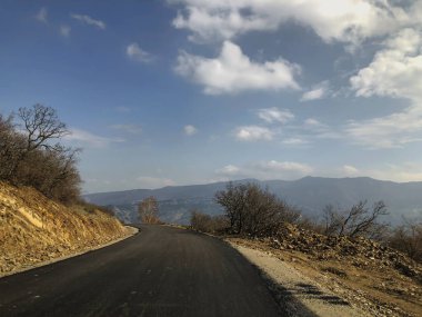 Yeni kır yolda asfalt döşenmiş. Dağların, uzayın, gökyüzünün, bulutların manzarası