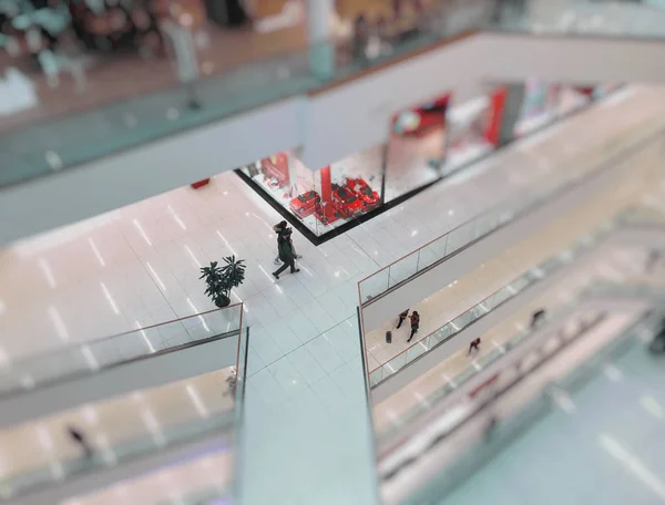 Los pisos en el interior moderno del centro comercial, barandillas de vidrio, personas caminando por los pisos, efecto desenfoque — Foto de Stock