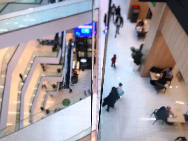 The floors in the modern interior of the shopping center, glass railings, people walking on the floors, blur effect