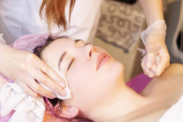 Young woman receiving facial epilation close up. Cosmetologist removes hair on face. Beauty salon, mustache depilation