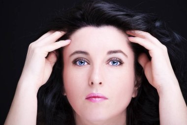 Uzun siyah saçlı, esmer, çekici bir kadın.