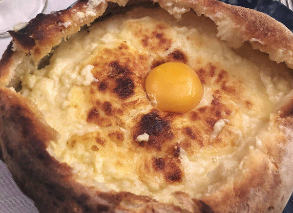 Georgian national cuisine - freshly baked adjarian khachapuri on the plate at the restaurant