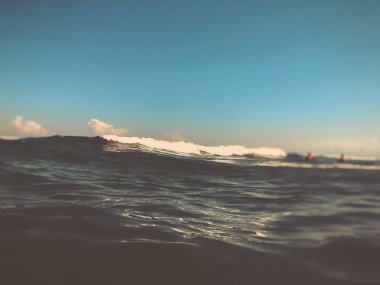 Deniz dalgasını su sıçratarak kapatın. Kumlu plajda güzel deniz dalgası ön görünümü. Yaz güneşli gün, mavi gökyüzü, su arka plan. Bulanıklaştırma efekti