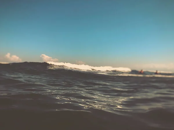 Κοντινό κύμα θαλάσσιου κύματος με σταγόνες. Μπροστινή θέα σε όμορφο κύμα θάλασσας στην αμμώδη παραλία. Καλοκαιρινή ηλιόλουστη μέρα, μπλε ουρανός, φόντο στο νερό. Εφέ θολώματος — Φωτογραφία Αρχείου