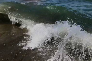 Deniz dalgasını su sıçratarak kapatın. Kumlu plajda güzel deniz dalgası ön görünümü. Yaz güneşli gün, su arka plan