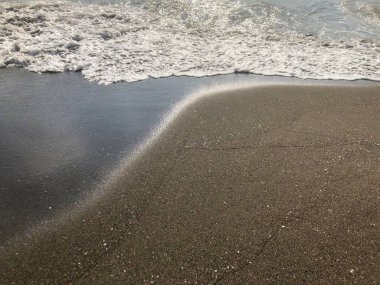 Gün batımında deniz manzarası. Kumlu bir sahilde parıltı lı dalgalar. Yaz güneşli gün, su arka plan