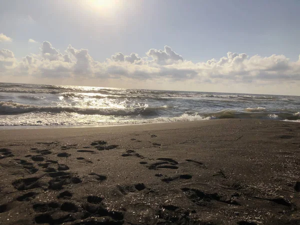 Vista del mar, el cielo y las nubes al atardecer. Olas brillantes en una playa de arena. Día soleado de verano, fondo de agua — Foto de Stock