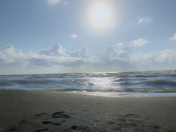 Vista del mar, el cielo y las nubes al atardecer. Olas brillantes en una playa de arena. Día soleado de verano, fondo de agua — Foto de Stock