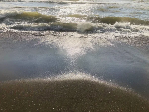 Utsikt över havet under solnedgången. Glitter vågor på en sandstrand. Sommar solig dag, vatten bakgrund — Stockfoto