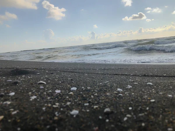 Uitzicht op de zee, de hemel en de wolken tijdens zonsondergang. Glitter golven op een zandstrand. Zomer zonnige dag, water achtergrond — Stockfoto