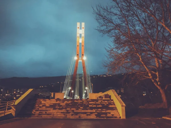 Zone de trottoir passant par un pont à haubans avec de gros câbles en acier, gros plan la nuit dans des lumières vives — Photo