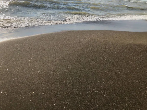 Vista del mar al atardecer. Olas brillantes en una playa de arena. Día soleado de verano, fondo de agua — Foto de Stock