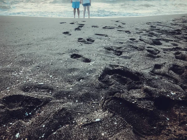 Reflexiones de personas de pie en la orilla del mar. Olas brillantes en una playa de arena. Día soleado de verano, fondo arenoso — Foto de Stock
