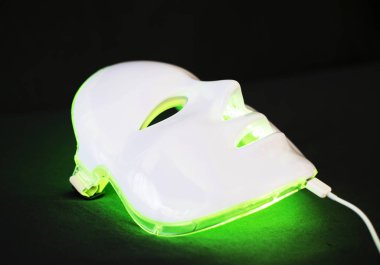 Siyah arka plan üzerine yüz cilt tedavisi için maske gençleştirici ışık.