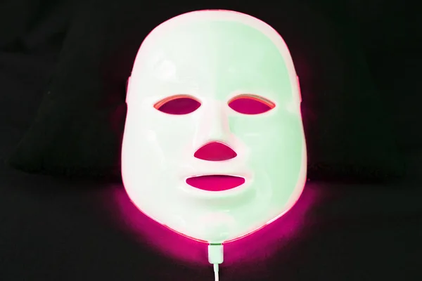 Light rejuvenating mask for facial skin therapy on black background.