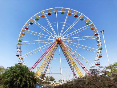 büyük beyaz dönme dolap ile arka planda bir gökdelen mavi gökyüzü karşı vurgulanır