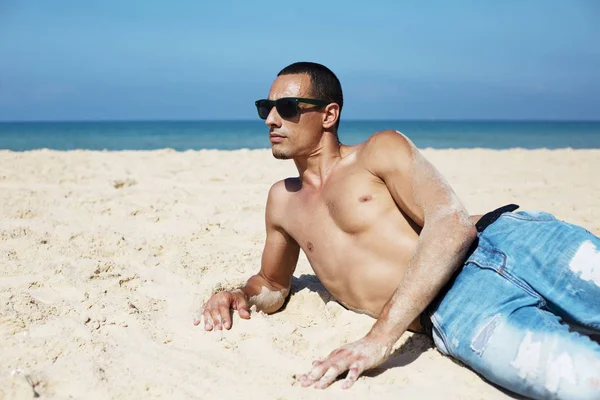 Joven musculoso descansando y posando en la playa — Foto de Stock
