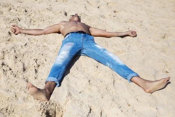 Jonge gespierde man rusten en poseren op het strand — Stockfoto