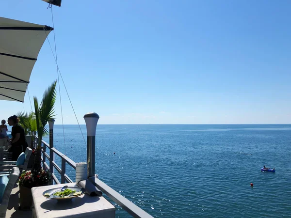 Restaurante en el muelle. Día soleado junto al mar. Balneario. Hermosa vista al mar. Efecto desenfoque — Foto de Stock