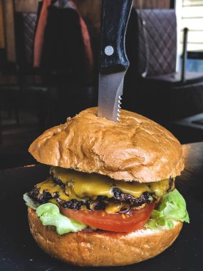 Amerikan mutfağı konsepti. Büyük bir klateyta, domates, salatalık, ketçap ve salata ile sulu bir et burger.. 