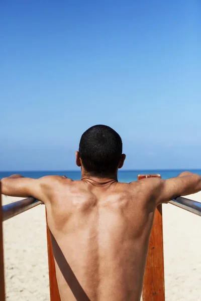 Een mannelijke atleet met een naakte romp traint op een horizontale balk — Stockfoto