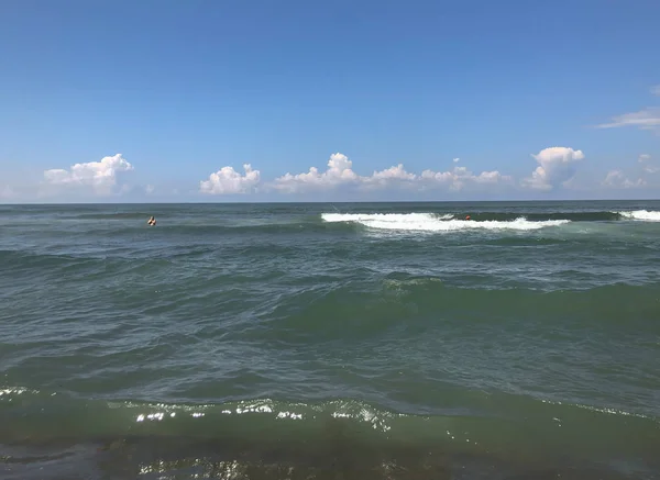 Primer plano de ola marina con salpicaduras. Vista frontal sobre hermosa ola marina en la playa de arena. Día soleado de verano, fondo de agua — Foto de Stock