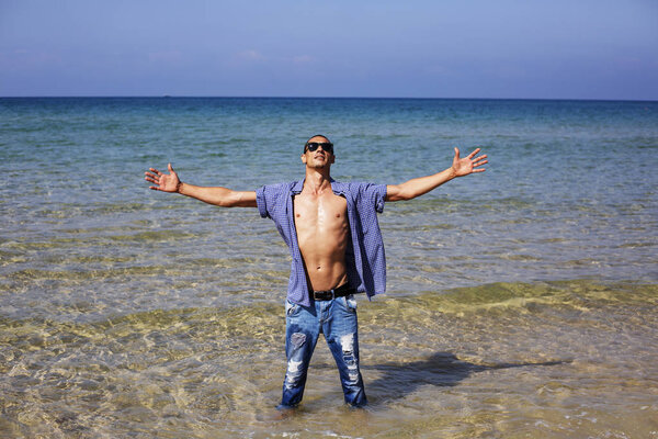 young muscular man posing and standing with outspread hands